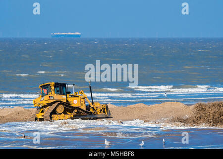 Bulldozer used for sand replenishment / beach nourishment to make wider beaches to reduce storm damage to coastal structures along the Belgian coast Stock Photo