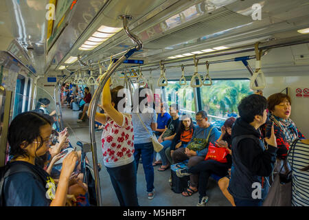 SINGAPORE, SINGAPORE - JANUARY 30, 2018: Indoor view of people in a rail commuters ride a crowded Mass Rapid Transit MRT train through the city centre Stock Photo