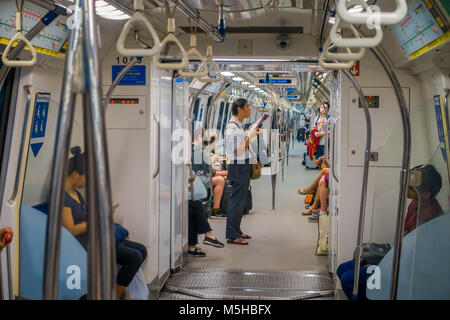 SINGAPORE, SINGAPORE - JANUARY 30, 2018: Indoor view of people in a rail commuters ride a crowded Mass Rapid Transit MRT train through the city centre Stock Photo