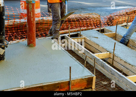 Construction worker leveling concrete pavement. Masonry construction workers smooth freshly poured concrete using bullfloat Stock Photo