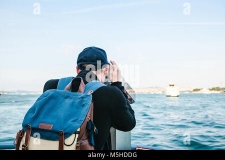 Man looking at the sea through tourist telescope. Stock Photo