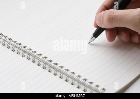 a ballpoint pen was holding in hand ready to writing in note book Stock Photo