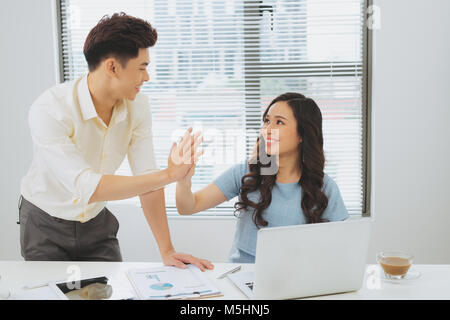 Couple of young designers working at modern office, two coworkers discussing fun project over a laptop Stock Photo