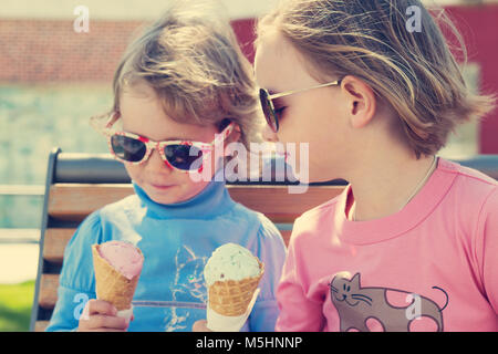 Two little girls (sisters) eating ice cream. Stock Photo