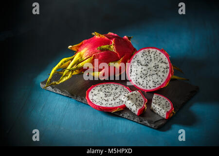 Raw organic dragon fruit ready to eat on black slate Stock Photo