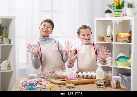 Child girl and boy cooking in home kitchen, showing hands with flour. Stock Photo