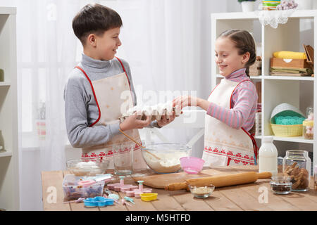 Child girl and boy cooking in home kitchen, hold eggs in the hands Stock Photo