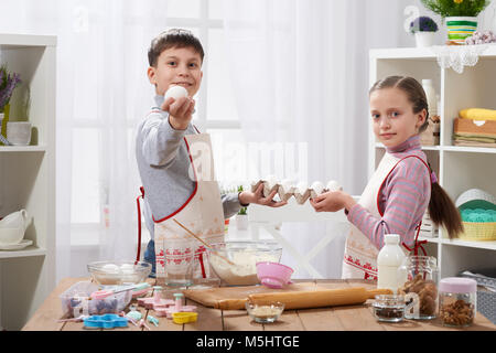 Child girl and boy cooking in home kitchen, hold eggs in the hands Stock Photo