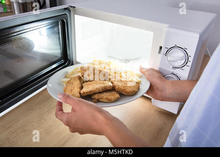 https://l450v.alamy.com/450v/m5htkd/close-up-of-a-persons-hand-heating-fried-food-in-microwave-oven-m5htkd.jpg