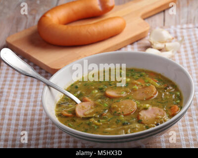 Dutch pea soup snert with smoked sausage Rookworst on a rustic table Stock Photo