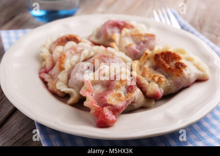 Traditional Polish dumplings Pierogi ruskie with sour cherry on a rustic table Stock Photo