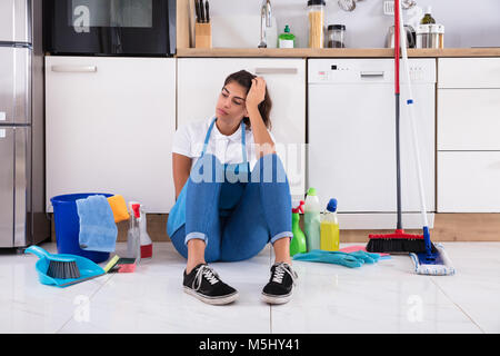 Premium Photo  Tired housewife with cleaning tools is sitting on