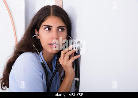 Young Curious Women Listening Through Wall Using Stethoscope Stock Photo