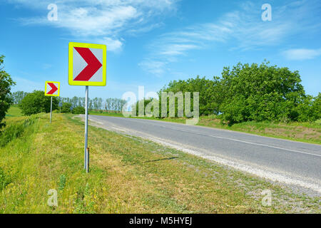 Warning signs for dangerous turn on country road. Stock Photo