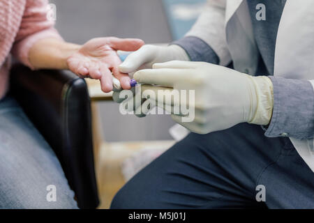 Pharmacist measuring blood sugar of customer in pharmacy Stock Photo