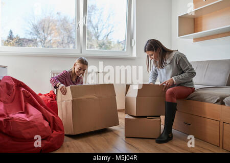 Two young women unpacking cardboard boxes in a room Stock Photo