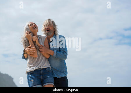 Affectionate senior couple standing on the beach Stock Photo