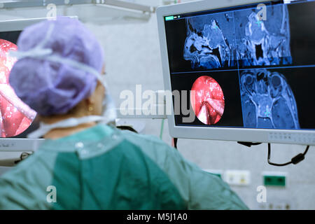 Neurosurgeon in scrubs looking at monitor Stock Photo