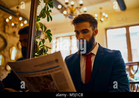 Elegant man reading newspaper in a cafe Stock Photo