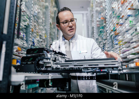 Pharmacist examining commissioning machine in pharmacy Stock Photo