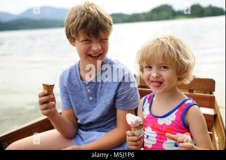 Portrait of little girl sitting in rowing boat with her brother eating icecream Stock Photo