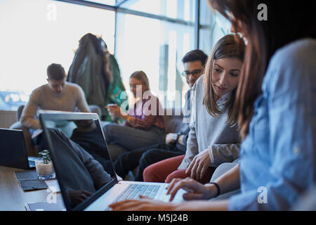 Group of friends sitting together in a cafe with laptop Stock Photo
