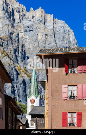 Schweiz, Kanton Wallis, Leukerbad, Ortskern, Katholische Kirche, Haus mit roten Fensterläden, Bergmassiv Leeshörner, Felswand Stock Photo