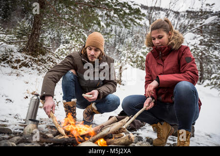 Couple on a trip in winter having a break at camp fire Stock Photo