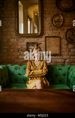Portrait of smiling elegant woman sitting on a couch Stock Photo