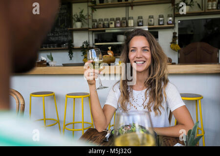 Smiling woman with glass of wine looking at man in a cafe Stock Photo