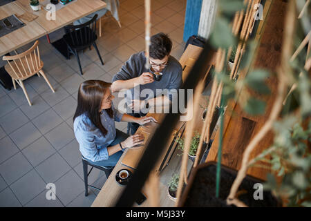 Young woman and man in a cafe with laptops talking and drinking espresso Stock Photo
