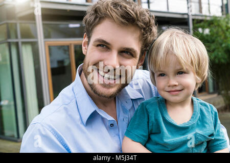 Portrait of smiling father with son in front of their home Stock Photo