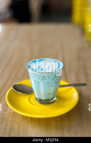 Blue smurf latte with spirulina in glass on yellow saucer Stock Photo