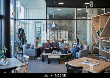 Group of friends sitting together in a cafe with laptop Stock Photo