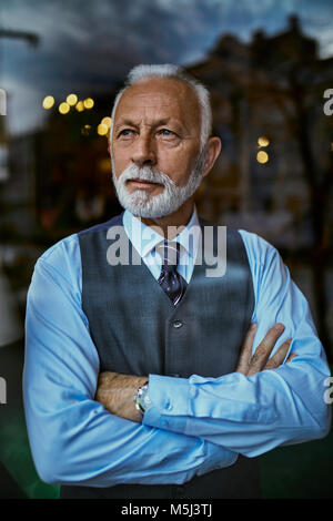 Elegant senior man looking out of window Stock Photo