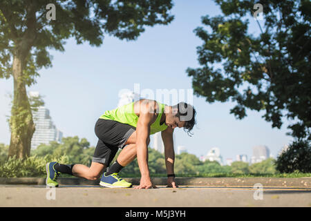 Runner training start position on street in urban park