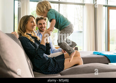 Happy parents playing with son on sofa at home Stock Photo