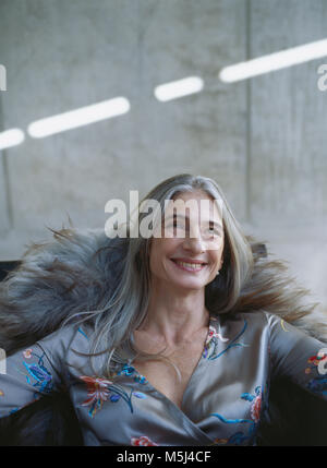 Portrait of laughing mature woman sitting in armchair Stock Photo