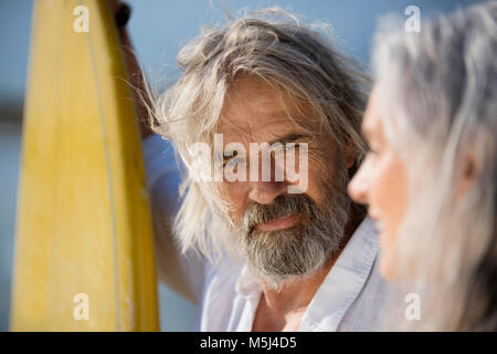 Affectionate senior couple with surfboards at beach Stock Photo