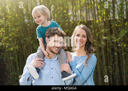 Portrait of happy family in garden in front of bamboo plants Stock Photo