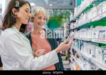 Pharmacist advising customer with cosmetics in pharmacy Stock Photo