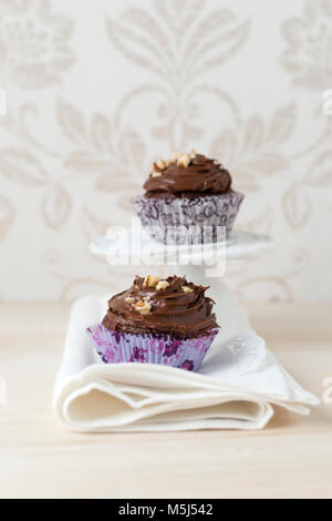 Two cup cakes with chocolate cream and cracked walnuts in paper cup Stock Photo