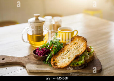Crusty bread with green salad and beetroot on wooden plate and green tea in cafe Stock Photo