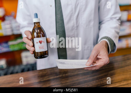 Pharmacist holding flask and prescription in pharmacy Stock Photo