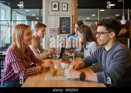 Group of friends sitting together in a cafe with laptop, smartphones and drinks Stock Photo
