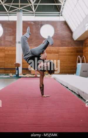 Young man doing acrobatic exercise in gym Stock Photo