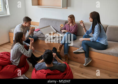 Group of students in dormitory eating pizza together Stock Photo