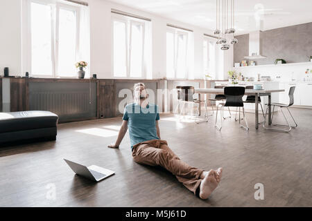 Man with eyes closed sitting on the floor in a loft relaxing Stock Photo