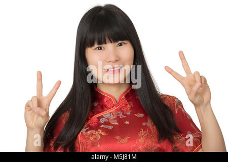 Beautiful Chinese woman wearing a traditional dress known as a Cheongsam or Chipao and giving the peace sign hand gesture isolated on a white backgrou Stock Photo