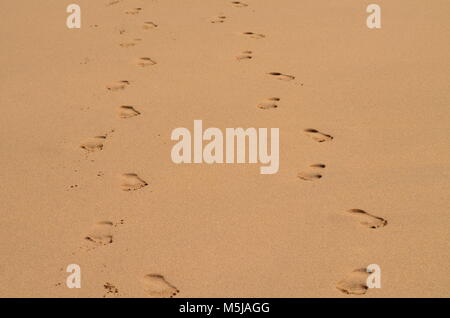 Two sets of footprints, side by side in the colored sand on the shores of Hawaii, meaning together forever. Stock Photo